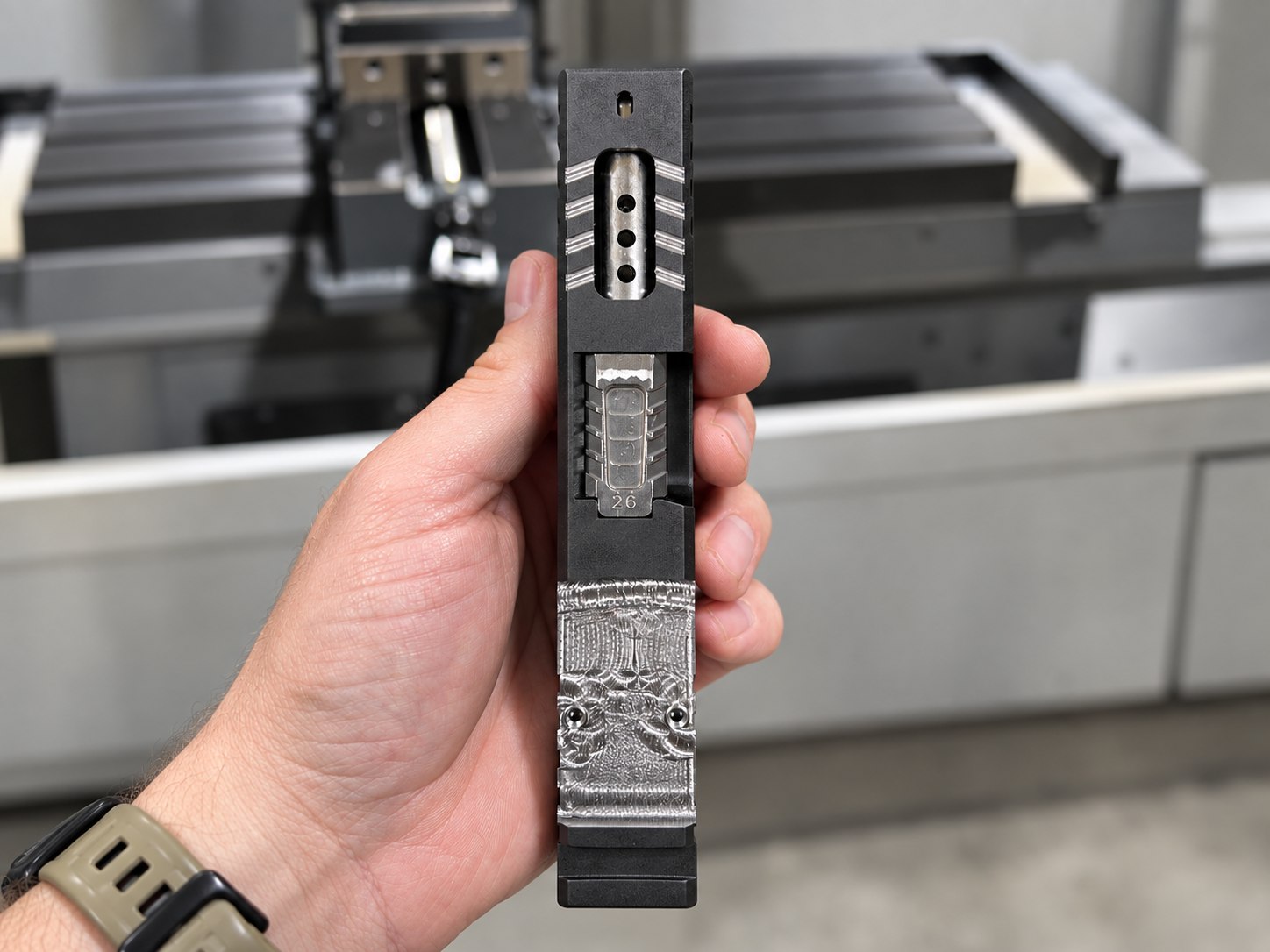 Hand holding a firearm slide and barrel with an RMR optic cut, porting, and top serrations